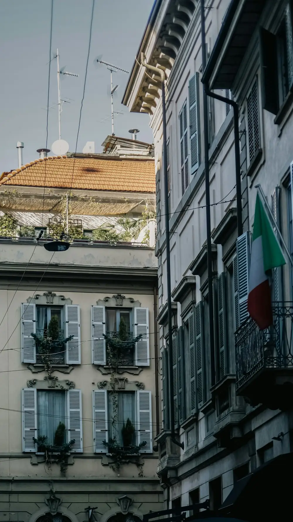Facciate di Milano con persiane, piante sui balconi e il tricolore