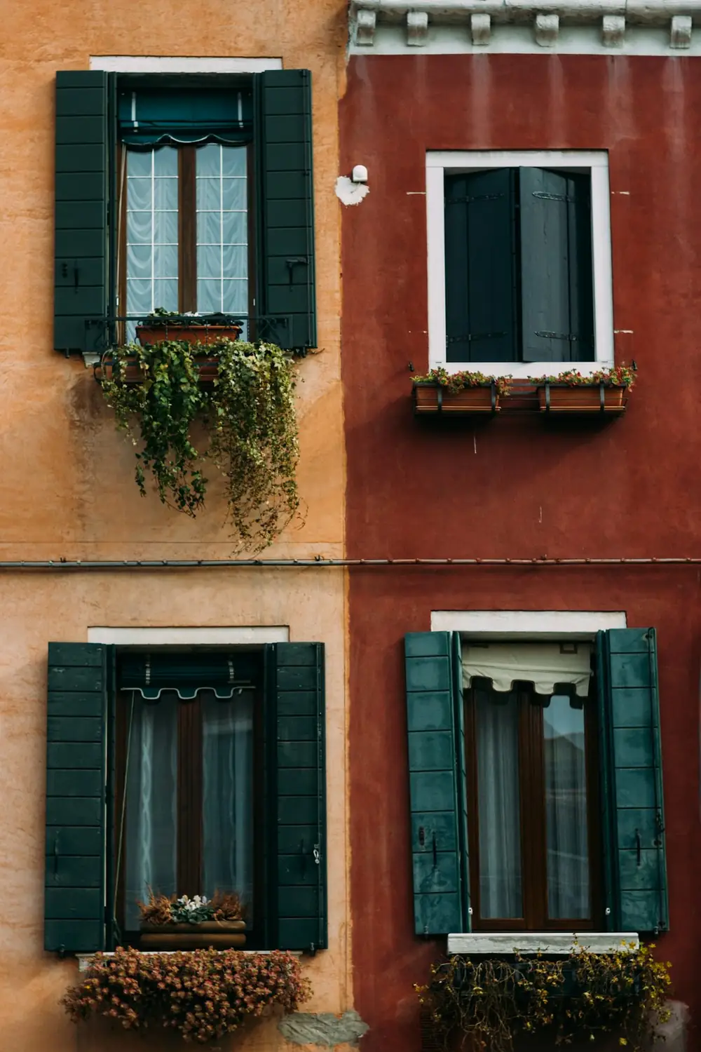 Finestre con persiane verdi su muri arancio e rosso